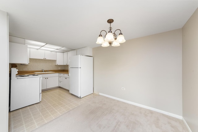 kitchen with white appliances, baseboards, white cabinetry, a sink, and hanging light fixtures