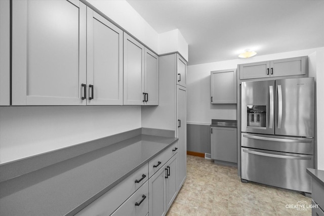 kitchen with dark countertops, stainless steel fridge with ice dispenser, and gray cabinetry