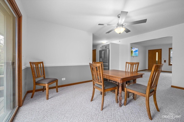 dining area featuring light carpet, baseboards, and ceiling fan