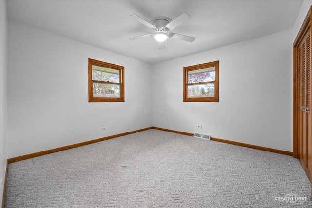 unfurnished room featuring plenty of natural light, carpet floors, baseboards, and visible vents