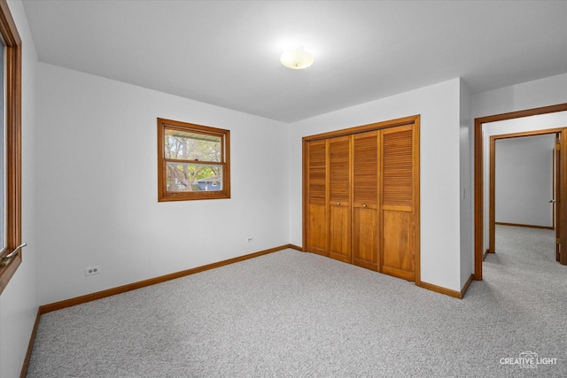 unfurnished bedroom with baseboards, carpet flooring, and a closet