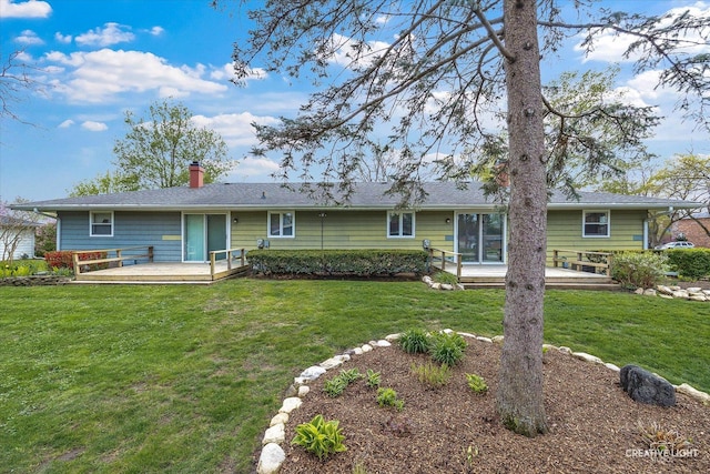 rear view of house with a yard, a deck, and a chimney