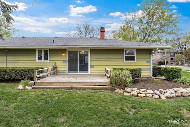 back of property featuring a chimney, a deck, and a lawn