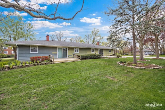 back of house featuring a deck, a chimney, and a lawn
