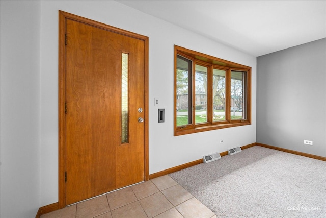 foyer featuring baseboards, light tile patterned floors, and visible vents