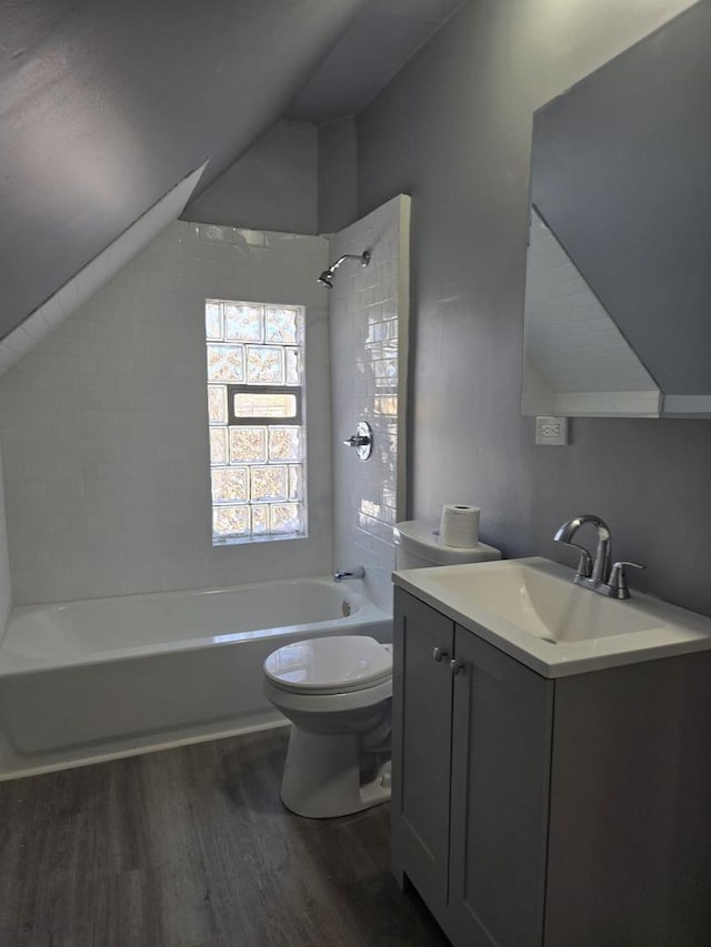 full bathroom with washtub / shower combination, vanity, toilet, wood finished floors, and vaulted ceiling
