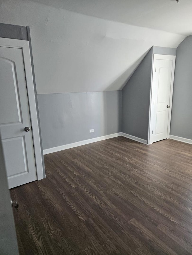 bonus room with baseboards, vaulted ceiling, and dark wood finished floors
