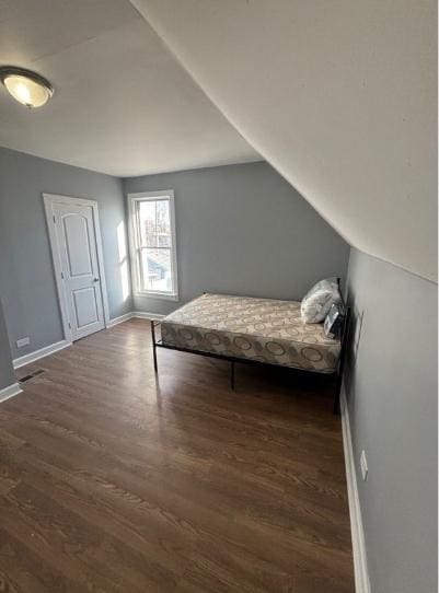 bedroom with baseboards, wood finished floors, and lofted ceiling