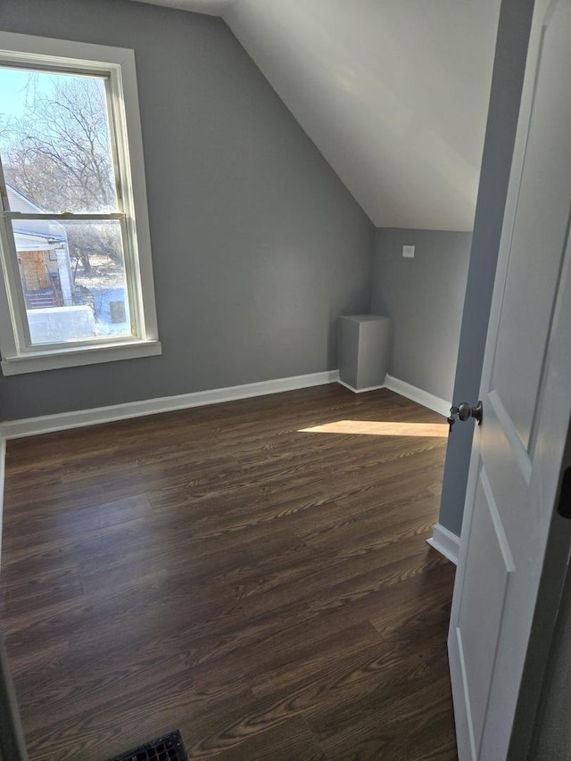 additional living space featuring baseboards, dark wood-type flooring, and lofted ceiling