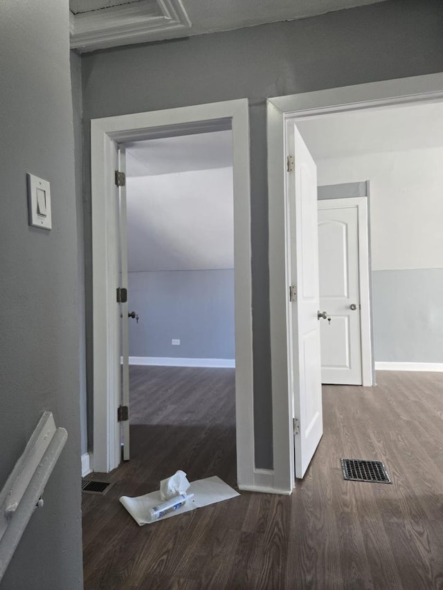 corridor featuring baseboards, visible vents, and wood finished floors