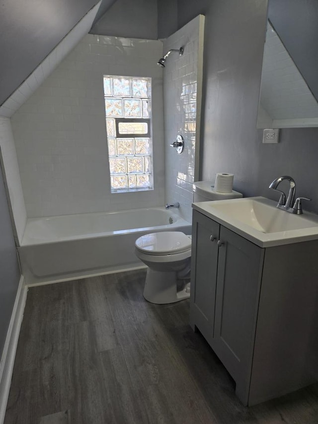 bathroom featuring vanity, wood finished floors, toilet, shower / bathing tub combination, and vaulted ceiling