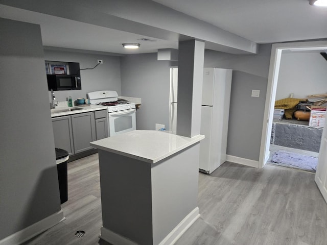 kitchen featuring visible vents, light countertops, baseboards, light wood finished floors, and white appliances