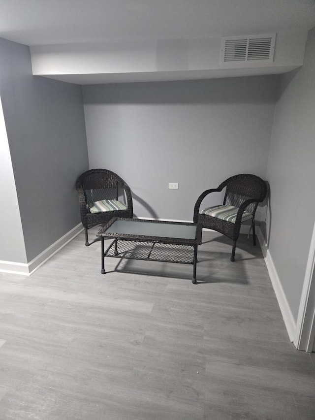 sitting room with baseboards, visible vents, and wood finished floors