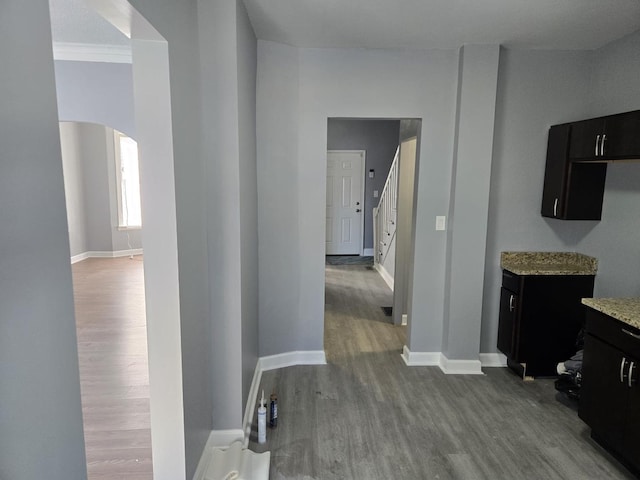 corridor with baseboards, arched walkways, and dark wood finished floors