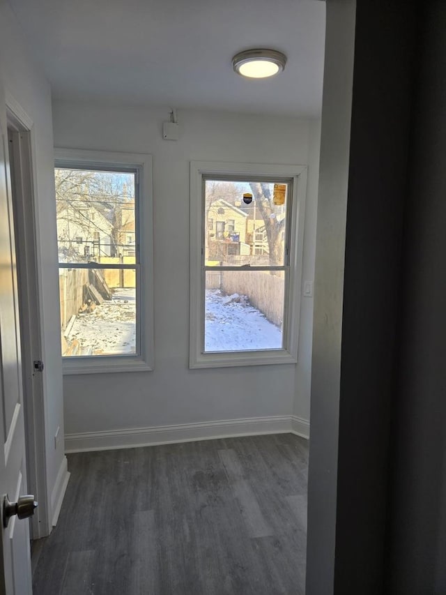 unfurnished room with baseboards and dark wood-style floors