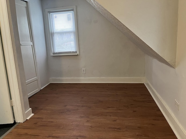 bonus room featuring baseboards and dark wood-type flooring