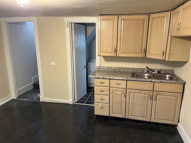 kitchen featuring a sink, baseboards, light brown cabinets, and washer / dryer