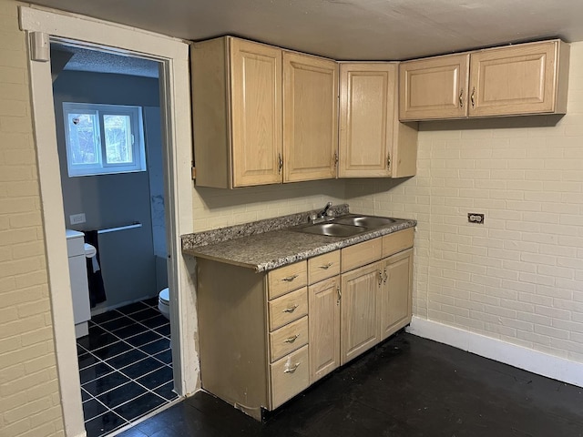 kitchen featuring a sink, light brown cabinetry, and baseboards