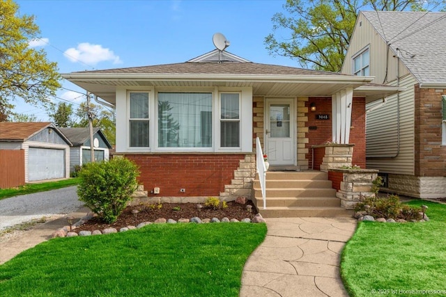 view of front facade featuring an outdoor structure, a shingled roof, a front yard, and brick siding