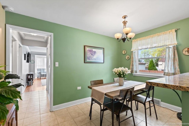 dining space with baseboards, light tile patterned floors, a chandelier, and visible vents
