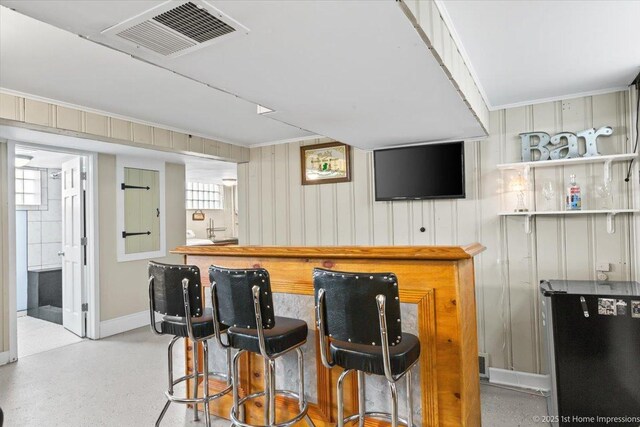 bar featuring crown molding, a dry bar, freestanding refrigerator, baseboards, and visible vents