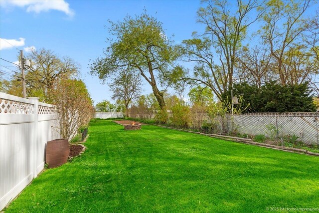 view of yard with a fenced backyard and a fire pit