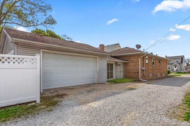 ranch-style home with an attached garage, a chimney, driveway, and brick siding