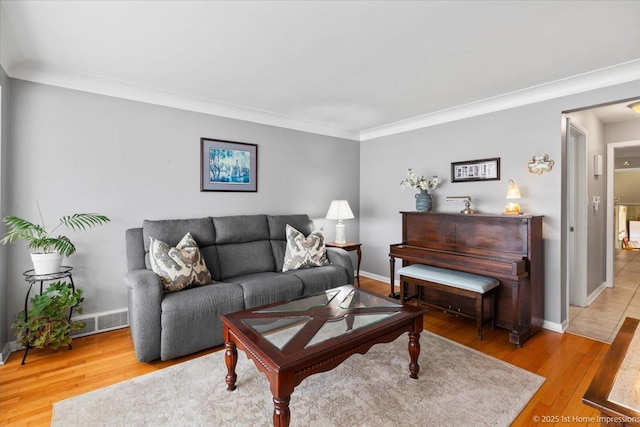 living area featuring crown molding, baseboards, and light wood-style floors