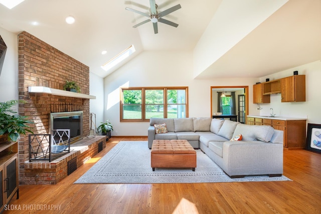 1 Byron Ct, Hawthorn Woods, IL 60047 - living room featuring a brick fireplace, light wood finished floors, a ceiling fan, a skylight, and high vaulted ceiling
