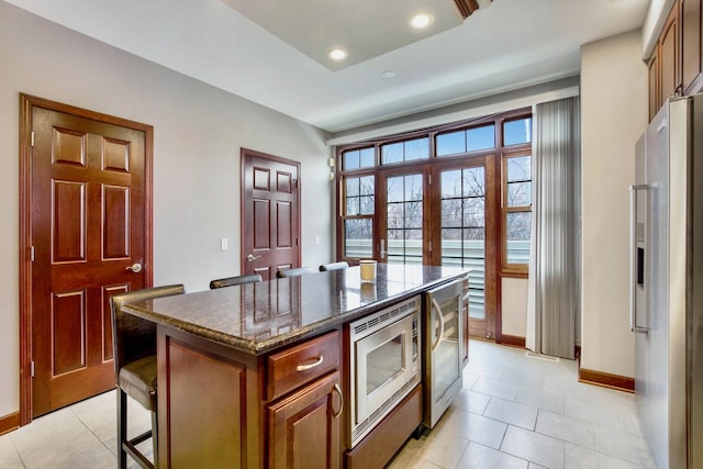 5912 N NW Hwy, Chicago, IL 60631 - kitchen featuring appliances with stainless steel finishes, light tile patterned floors, baseboards, dark stone countertops, and a center island