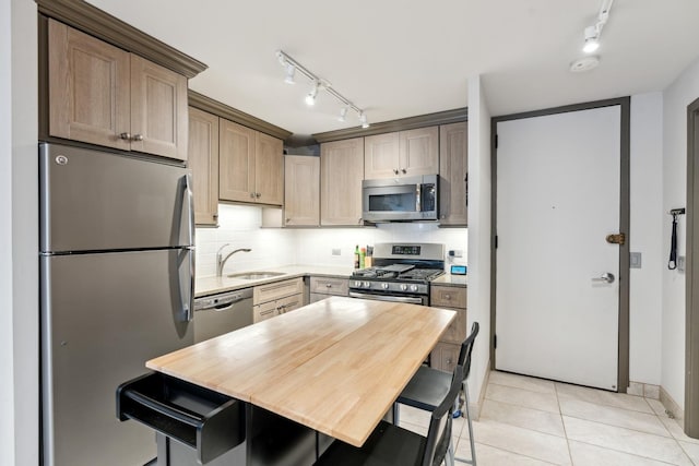 kitchen featuring track lighting, light countertops, a sink, backsplash, and stainless steel appliances