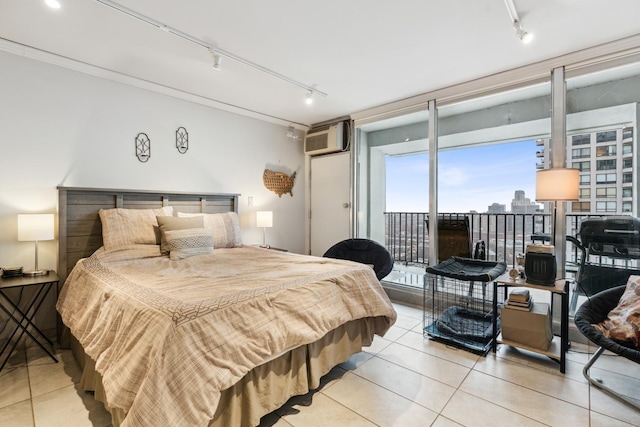 tiled bedroom featuring a wall of windows, an AC wall unit, rail lighting, and access to exterior
