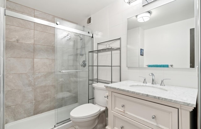 bathroom featuring vanity, visible vents, toilet, tile walls, and a shower stall