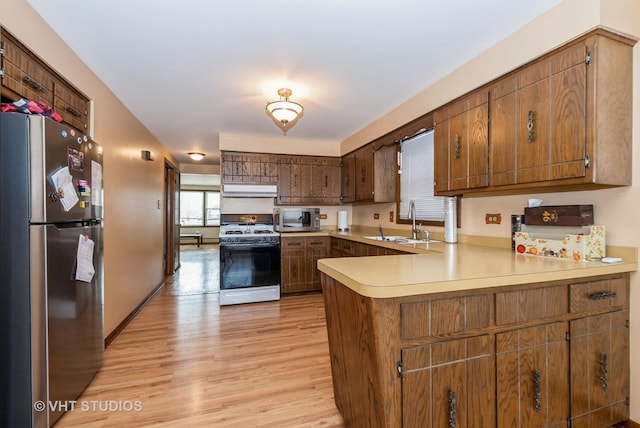 6004 S Kolmar Ave, Chicago, IL 60629 - kitchen with appliances with stainless steel finishes, a sink, a peninsula, light wood-type flooring, and under cabinet range hood