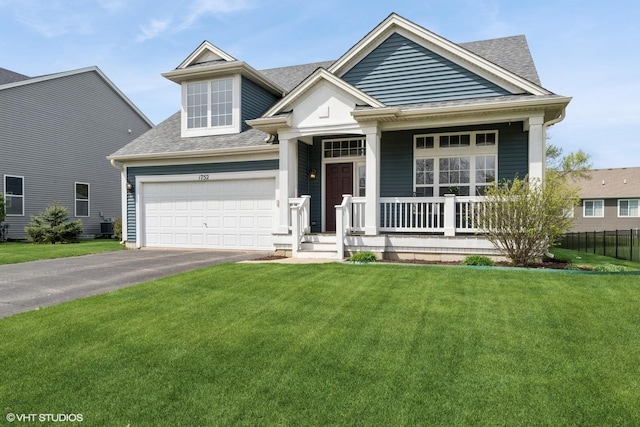view of front of house featuring covered porch, a garage, a shingled roof, and a front lawn