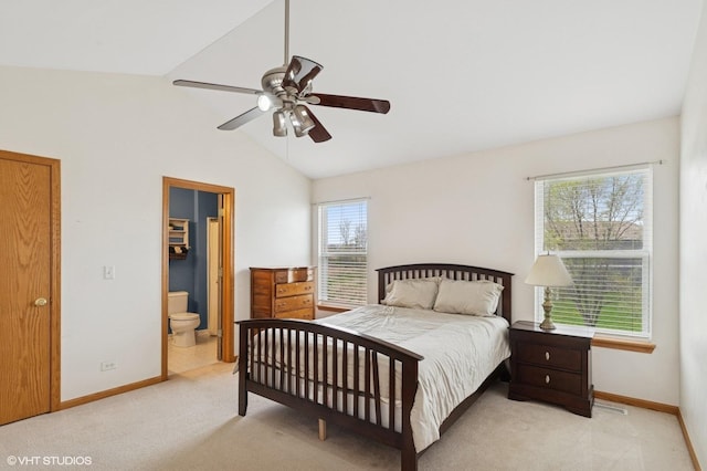 bedroom featuring light colored carpet, baseboards, ensuite bath, and vaulted ceiling