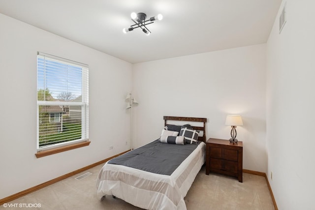 carpeted bedroom featuring a chandelier, baseboards, and visible vents