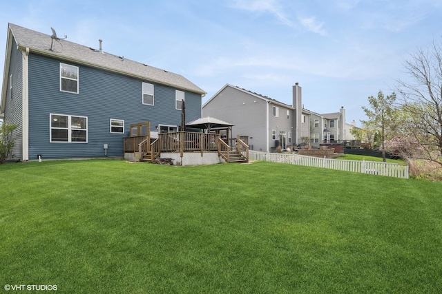 rear view of house featuring a lawn, fence, and a deck