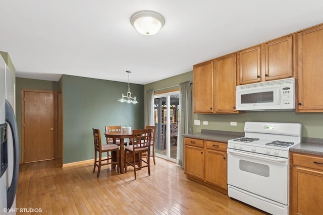 kitchen featuring light wood-style floors, brown cabinets, white appliances, and a chandelier
