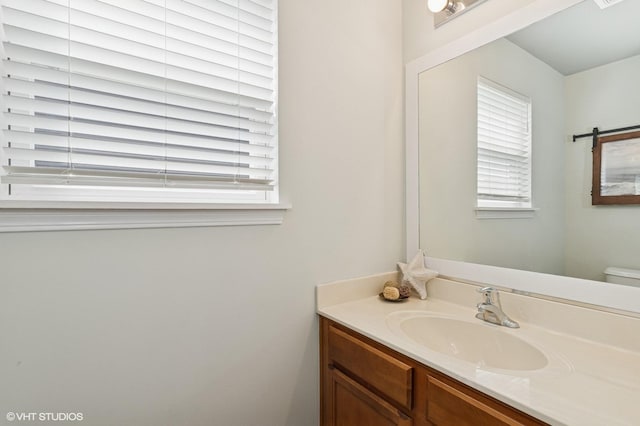 bathroom with a healthy amount of sunlight, vanity, and toilet
