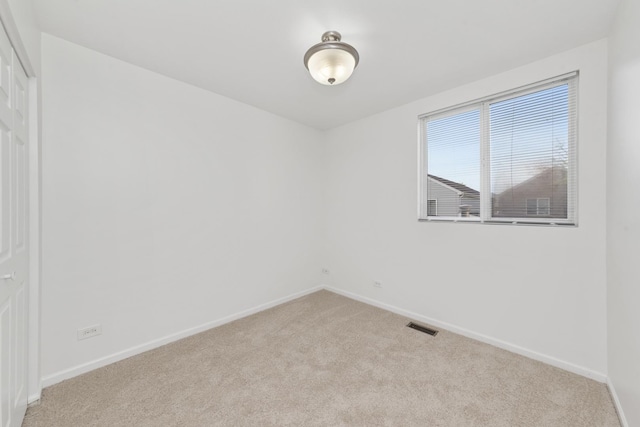 spare room with carpet floors, baseboards, and visible vents