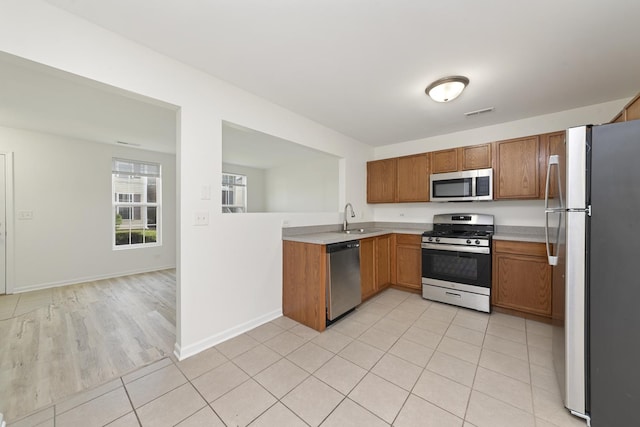 kitchen featuring visible vents, brown cabinets, a sink, light countertops, and stainless steel appliances