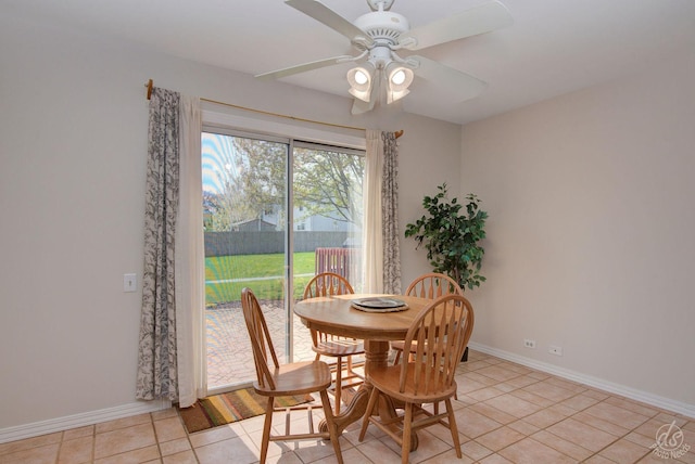 dining space with a ceiling fan, baseboards, and light tile patterned floors