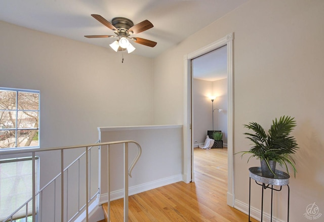 hall with baseboards, wood finished floors, and an upstairs landing