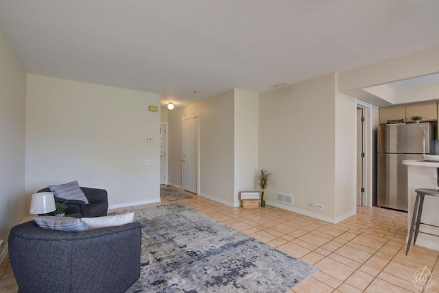 living area with baseboards, visible vents, and light tile patterned floors