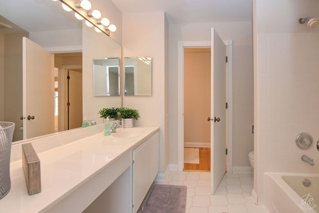 bathroom featuring toilet, tile patterned floors, baseboards, and vanity