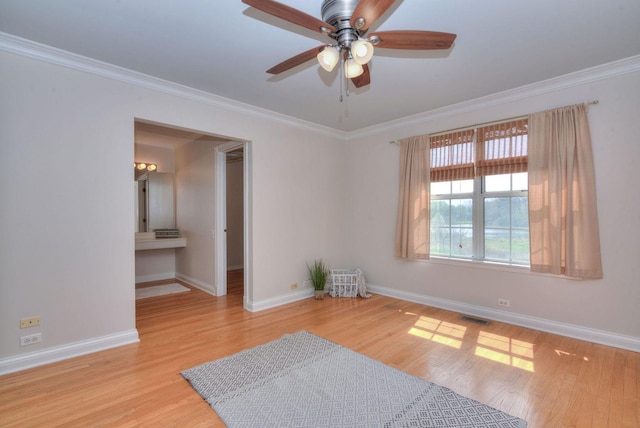 empty room with a ceiling fan, visible vents, crown molding, wood finished floors, and baseboards