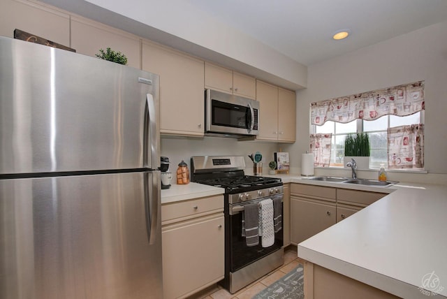 kitchen with cream cabinets, appliances with stainless steel finishes, a sink, light countertops, and recessed lighting
