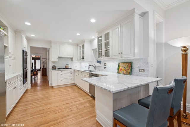 2535 N Burling St, Chicago, IL 60614 - kitchen featuring appliances with stainless steel finishes, a peninsula, a breakfast bar area, white cabinets, and ornamental molding