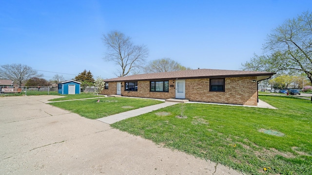 view of front of house with a front lawn, brick siding, a detached garage, a shed, and an outbuilding